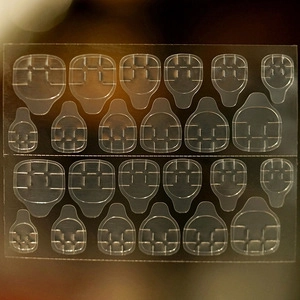 Close-up of transparent double-sided jelly glue tabs for press-on nails application