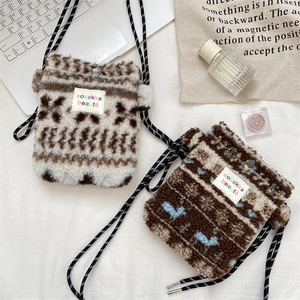 Détail de mini sacs en peluche avec bandoulières tissées sur un fond blanc propre