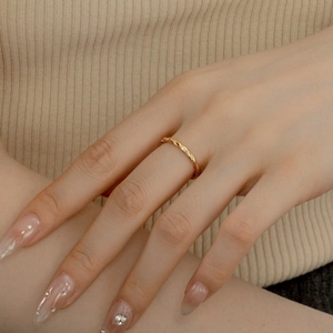Close-up of a gold twisted rope ring on a finger, featuring fine craftsmanship and texture