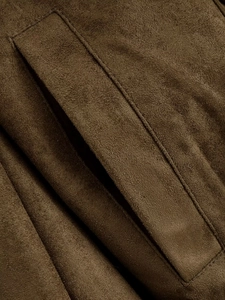 Détail de la veste en daim marron avec coutures de précision et texture de poche