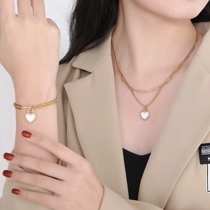 Detail of gold-toned double-layered necklace and bracelet with white heart pendants