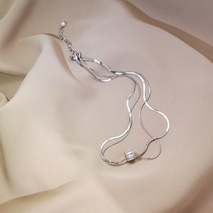 Close-up of double-layer silver snake chain with zircon cylinder pendant and pearl tail