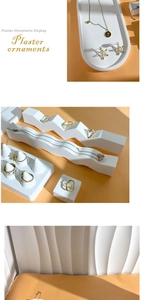 Modern white plaster wave and tray displays for jewelry presentation on orange background