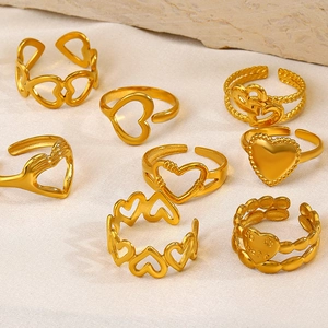 Collection of 18K gold plated stainless steel heart rings on textured fabric background