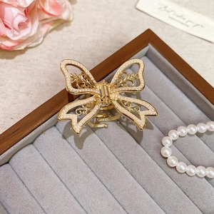Detail shot of a golden butterfly hair claw with white pearls and hollow leaf patterns