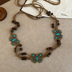 Detail of bohemian waist chain with wood beads and bronze butterfly pendants with blue stones
