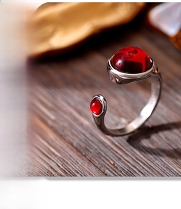Macro shot of retro stainless steel ring with red garnets on a vintage wooden surface