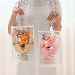 Close-up of artificial rose and sunflower bouquets in LED lit gift bags with ribbons
