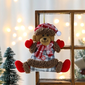 Brown plush Christmas bear ornament with red plaid hat and scarf hanging on a wooden stand