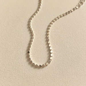 Minimalist S925 sterling silver anklet with flat beads on a textured background