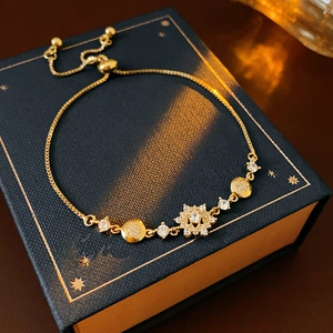 Détail d'un bracelet flocon de neige doré réglable avec zircon sur une boîte bleue