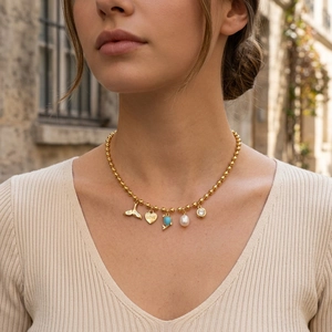 Gold-plated ball chain necklace with pearl, heart, and zircon charms on a model