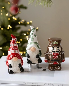 Detailed view of ceramic Christmas gnome and nutcracker seasoning jars on a white book