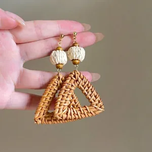 Detailed view of handmade raffia woven fan-shaped earrings with natural wooden beads