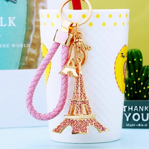 Detail of Eiffel Tower keychain with pink rhinestones and a braided cord on a decorative cup