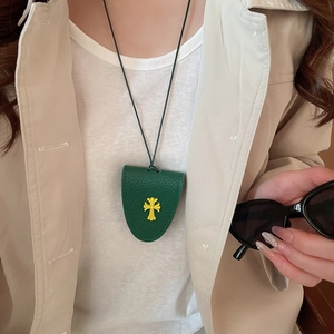 Detail of green leather glasses holder necklace with yellow cross emblem on a model