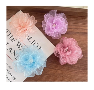 Detail von vier bunten Organza Blumen Haarklammern mit Perlen auf einer Holzoberfläche
