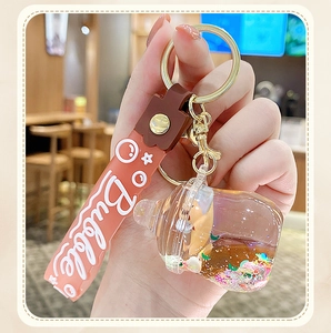 Detail of hand holding a milk tea bottle liquid keychain with floating glitters and charms