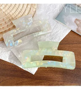 Detail of large iridescent acetate hair claws in pearlescent white and soft green