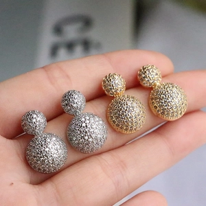 Macro detail of gold and silver double sphere stud earrings with micro-paved rhinestones