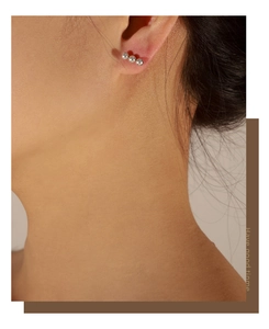 Close-up of three-bead silver metal stud earrings worn by a model in a minimalist style