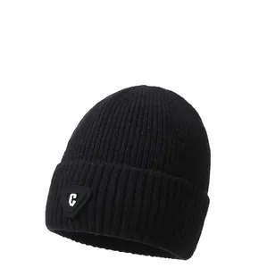 Detail of black ribbed knit beanie featuring thick fabric texture and metallic C logo badge