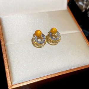 Elegant gold cat eye stone earrings with double halo zircon circles on beige jewelry box