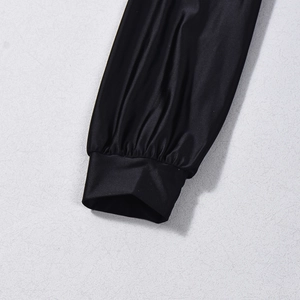 Close-up of elastic ruffled cuffs on a black long-sleeve top with silky fabric texture