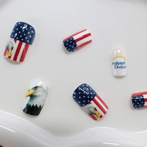 Press-on nails featuring American flag designs, bald eagle motifs, and blue letter accents