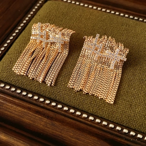 Détail macro de boucles d'oreilles à franges dorées avec zircons sur velours foncé