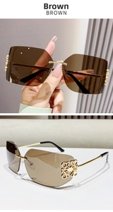 Detail view of brown gradient rimless sunglasses with ornate gold metal logo hinges