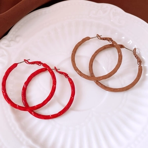 Detail of red and brown round hoop earrings with hammered texture on a ceramic plate
