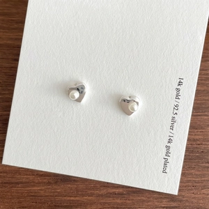 925 silver heart pearl stud earrings with polished mirror finish on textured wood background