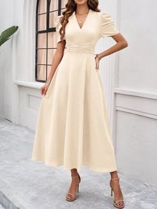 Close-up of elegant beige V-neck dress featuring pleated waist and subtle striped texture