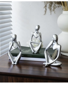 Detailed view of silver thinker sculptures on a wooden table in a home setting