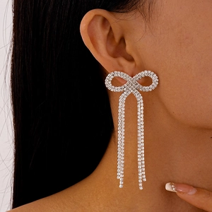 Gros plan de boucles d'oreilles nœud argenté avec de longs pompons en strass sur modèle