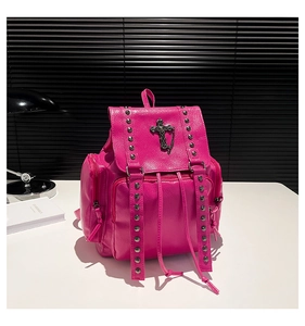 Detail of rose red backpack featuring silver studs and metal cross pendant decoration