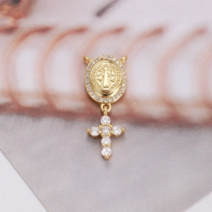 Macro view of gold pendant with San Benito medal and sparkling zircon cross