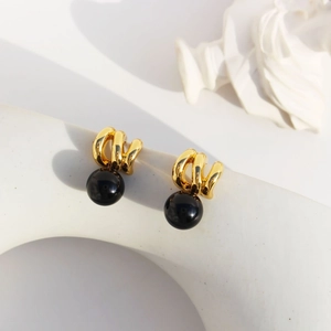Vintage gold wave earrings with black onyx bead on a minimalist artistic pedestal