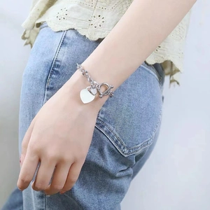 Bracelet argenté avec pendentif cœur et fermoir OT porté par un mannequin pour style