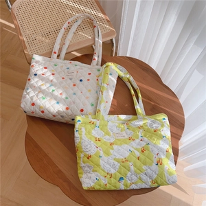 Detail of quilted tote bags with polka dot and duck prints on a wooden table