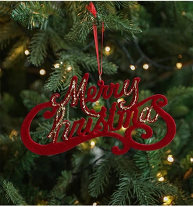 Close-up of red flocked Merry Christmas ornament with gold glitter on a festive tree