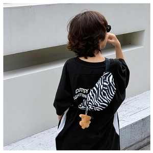 Detail of zebra print canvas chest bag for kids featuring a brown plush bear charm