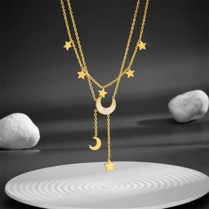 Gold double-layered star and moon necklace with white shell pendant on a white tray