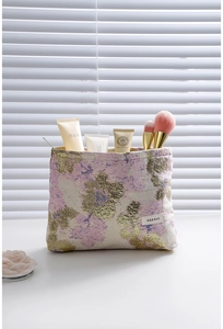 Détail de la trousse de maquillage en jacquard rose et doré avec des pinceaux cosmétiques