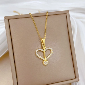 Macro shot of Cupid arrow and heart pendant with sparkling cubic zirconia in gold