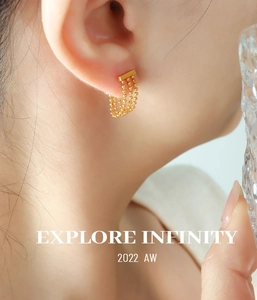 Gros plan de boucles d'oreilles dorées en acier titane avec triple chaîne perlée