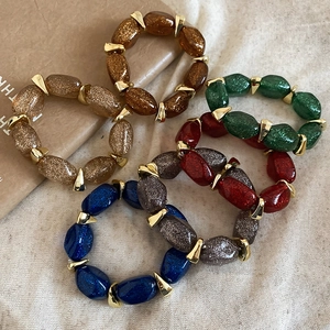 Detail of colorful acrylic pebble bead bracelets with gold metallic spacers and glitter