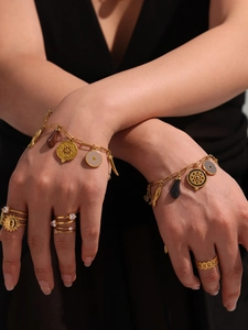 Close-up of gold drip oil charms bracelet and sunburst ring on model's hand
