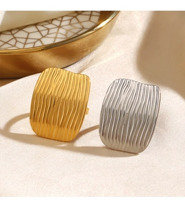 Macro detail of textured gold and silver rectangular rings on champagne velvet background